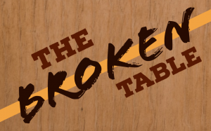 The text "The Broken Table" over a wood-texture background