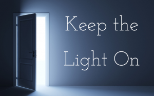 A darkened grey room with an open door spilling in light from the next space and the text "Keep the Light On"